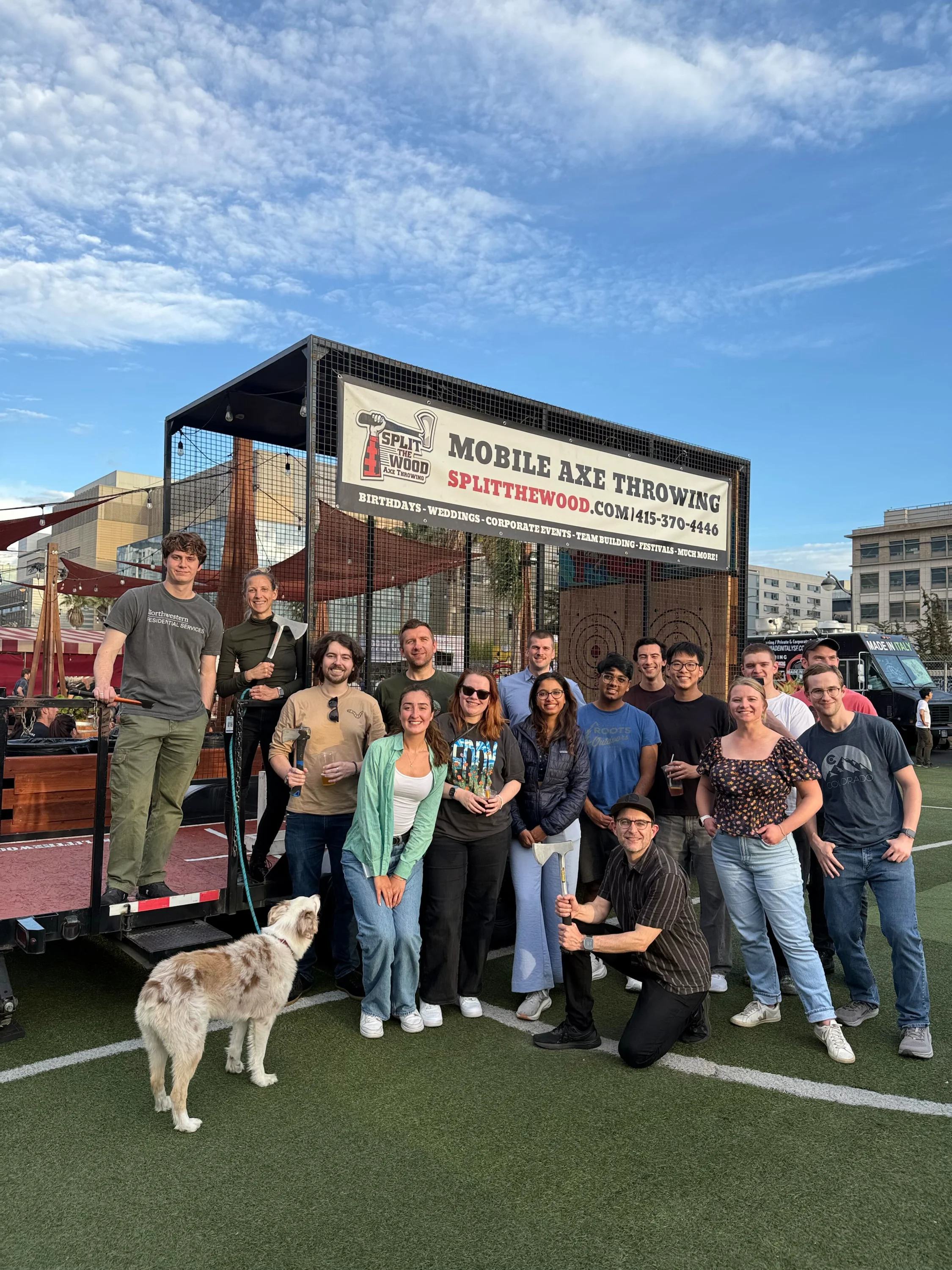 Notability teammates posing in front of a mobile axe-throwing cage, with a dog in the foreground
